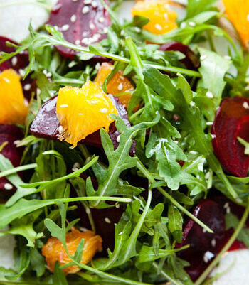 arugula salad with beets, orange, and toasted sesame seeds on a plate.