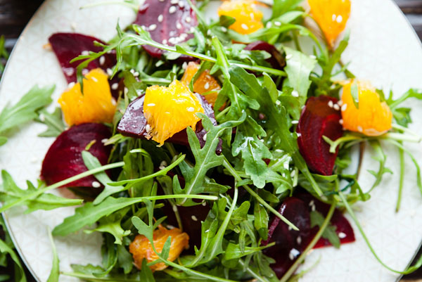 arugula salad with beets, orange, and toasted sesame seeds on a plate.
