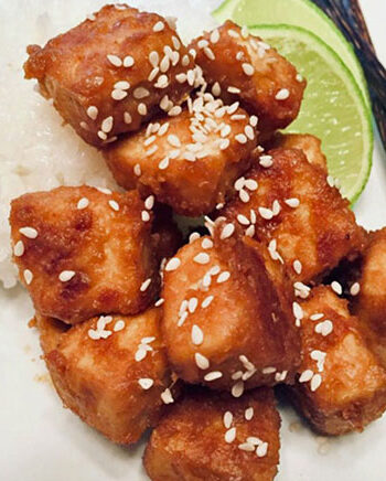 Baked peanut tofu with rice, a wedge of lime, and chopsticks