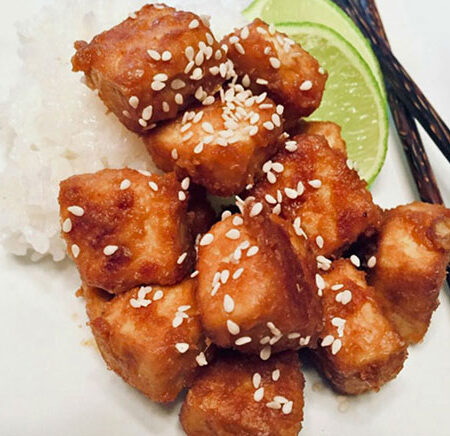 Baked peanut tofu with rice, a wedge of lime, and chopsticks