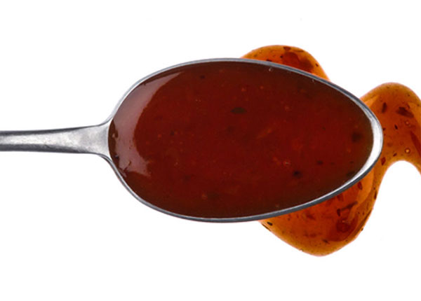 Asian tofu marinade on a spoon drizzled onto a white background.
