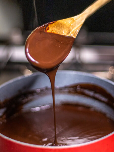 Chocolate sauce in a pot with a wooden spoon.