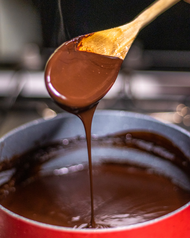 Chocolate sauce in a pot with a wooden spoon.