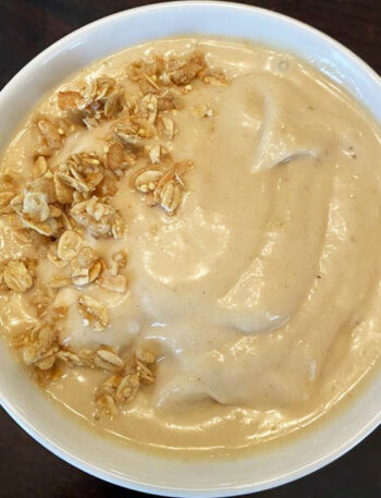 Banana peanut butter smoothie bowl, topped with granola.