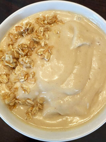 Banana peanut butter smoothie bowl, topped with granola.