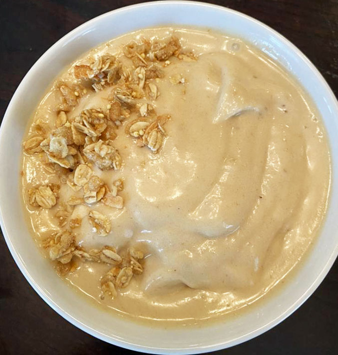 Banana peanut butter smoothie bowl, topped with granola.