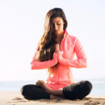 Woman meditating on a beach.
