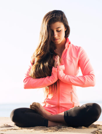 Woman meditating on a beach.