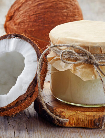 A halved coconut sitting next to a jar of coconut oil.