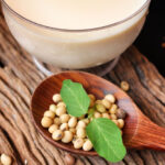 Soy beans and a glass of soy milk on a wooden table top.