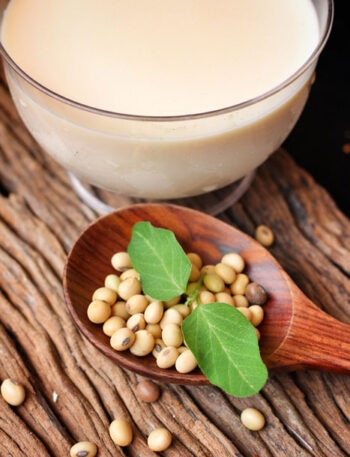 Soy beans and a glass of soy milk on a wooden table top.