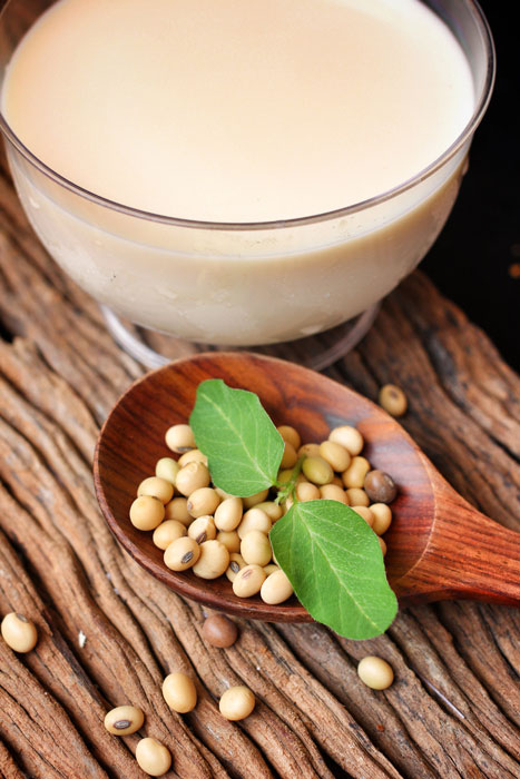 Soy beans and a glass of soy milk on a wooden table top.