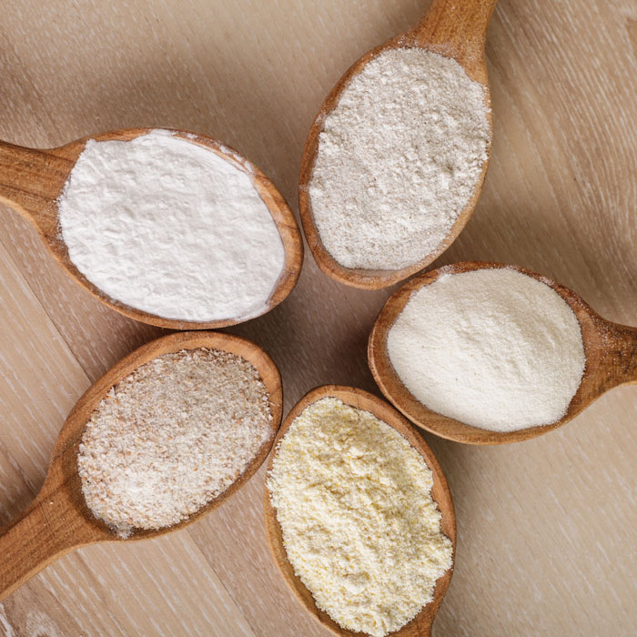 5 spoons holding different types of gluten-free flour.