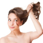 Young woman holding her long hair up and off to the side.