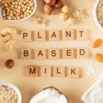 Nuts and grains used to make plant-based milk with the lettering "Plant Based Milk" arranged in the center.