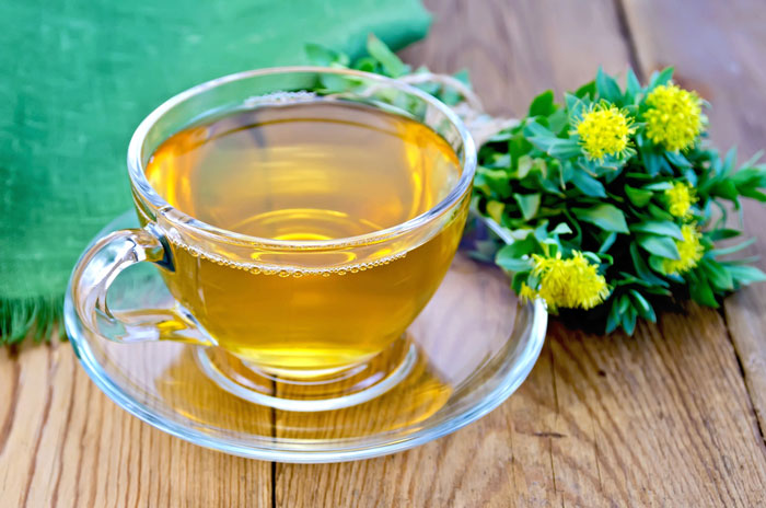 Cup of rhodiola tea next to a rhodiola plant/flower.