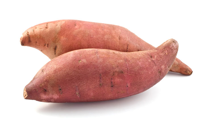 Two whole sweet potatoes on a white background.