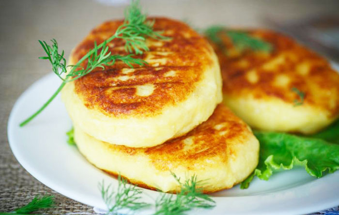 Three potato cakes on a white plate with a dill garnish.