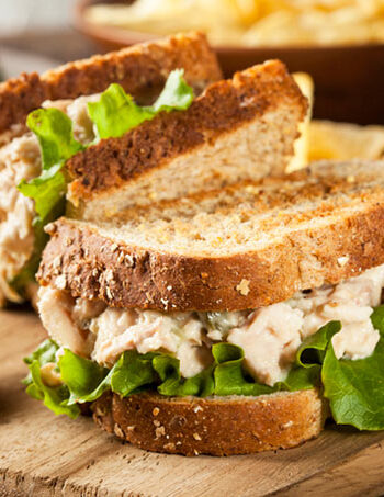 Toasted tuna fishless sandwich with lettuce and pickle on a wooden cutting board.