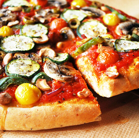 Veggie supreme pizza with a cut slice being pulled out.