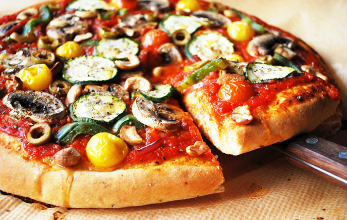 Veggie supreme pizza with a cut slice being pulled out.