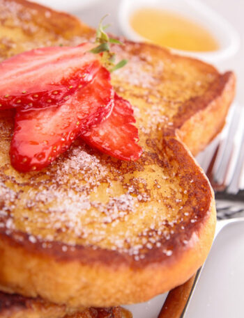 French toast with powdered sugar and cut strawberries.
