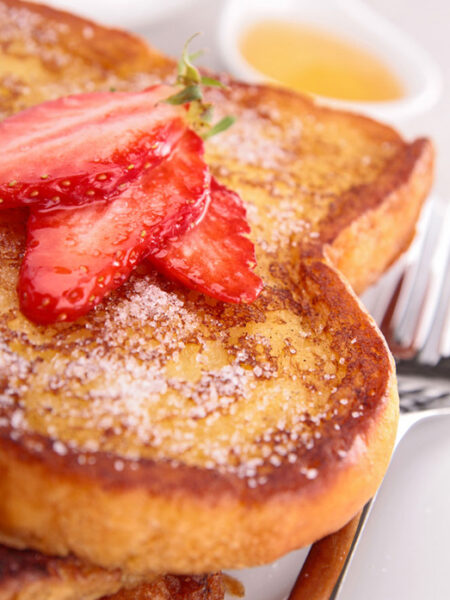 French toast with powdered sugar and cut strawberries.