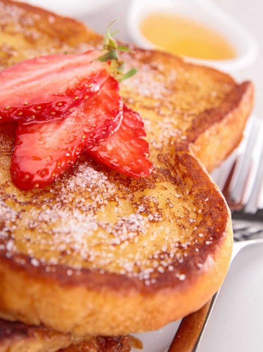 French toast with powdered sugar and cut strawberries.