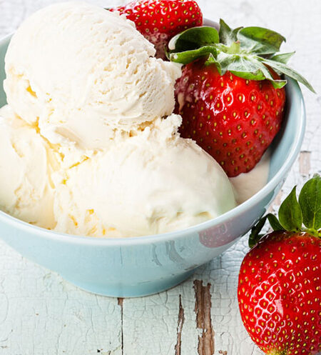 Bowl of vanilla ice cream with whole strawberries.