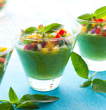 Individual servings of green gazpacho garnished with diced bell pepper.