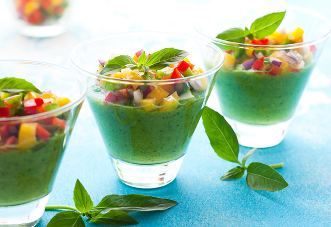 Individual servings of green gazpacho garnished with diced bell pepper.