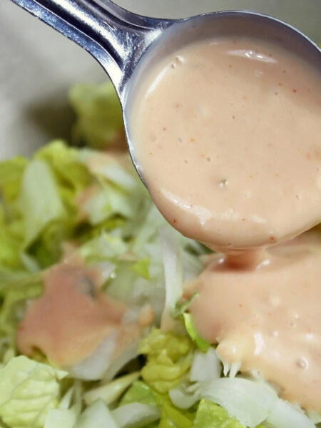 Spicy Vegan Thousand Island Dressing spooned over a green salad.