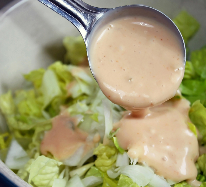 Spicy Vegan Thousand Island Dressing spooned over a green salad.