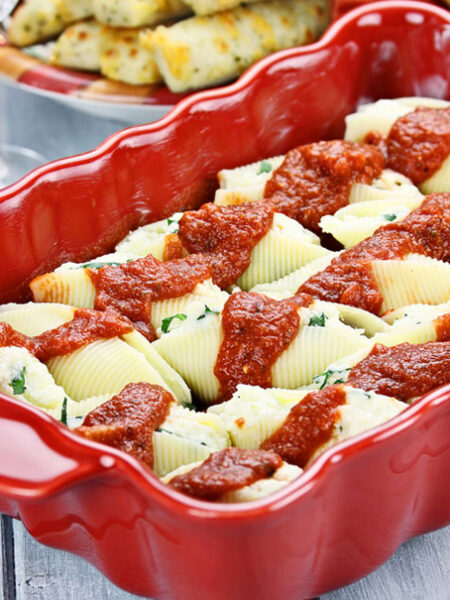 Red baking dish with vegan stuffed shells with marinara.
