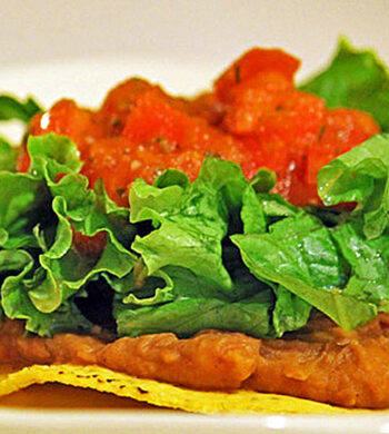 Tostada with homemade refried beans, topped with fresh lettuce and salsa.