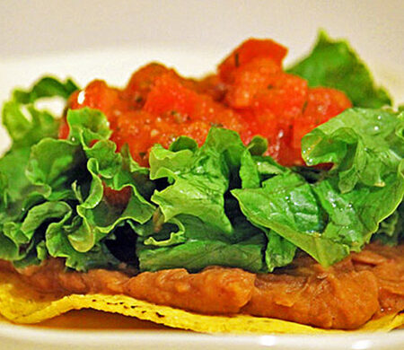Tostada with homemade refried beans, topped with fresh lettuce and salsa.
