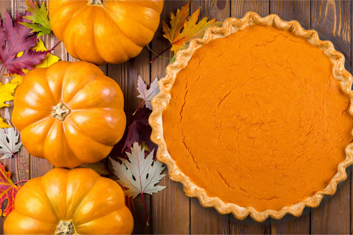 Creamy Vegan Pumpkin Pie next to 3 small pumpkins.